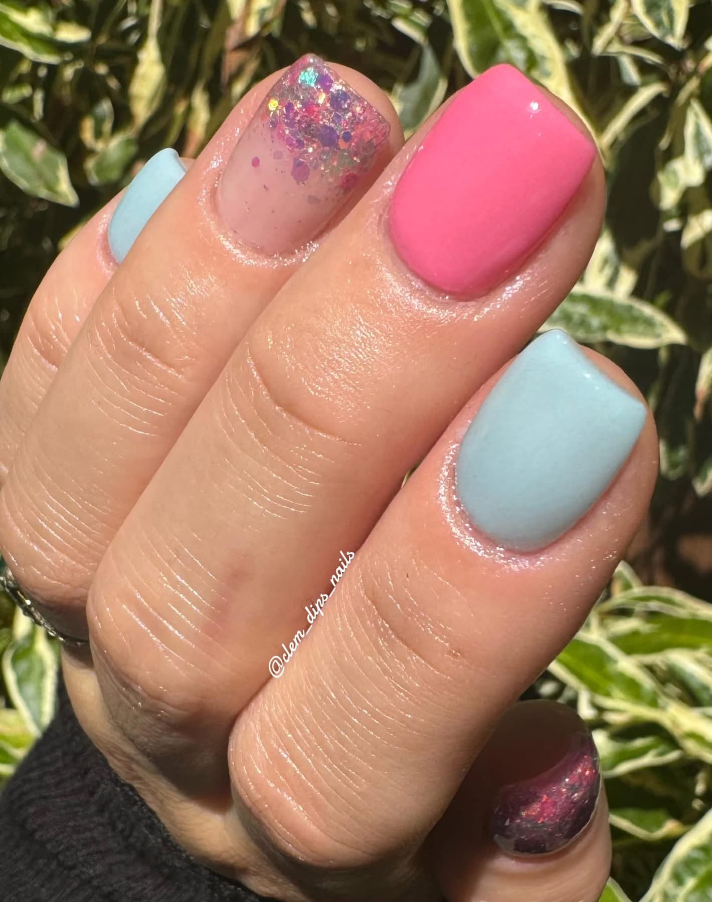 Manicure with glossy solid pink and light blue nails and nails with iridescent glitter over natural base.