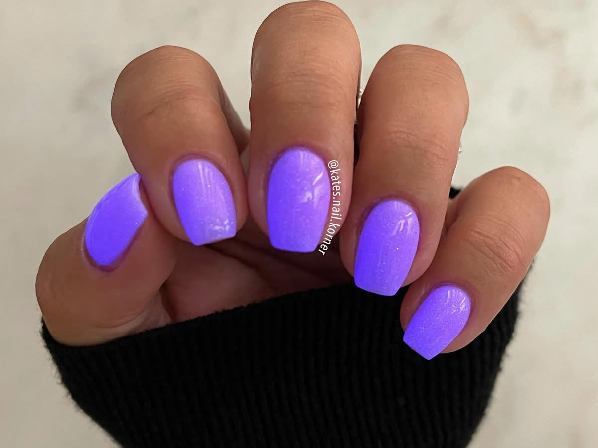Square nails with glossy, glowing purple gel polish on medium-length nails.