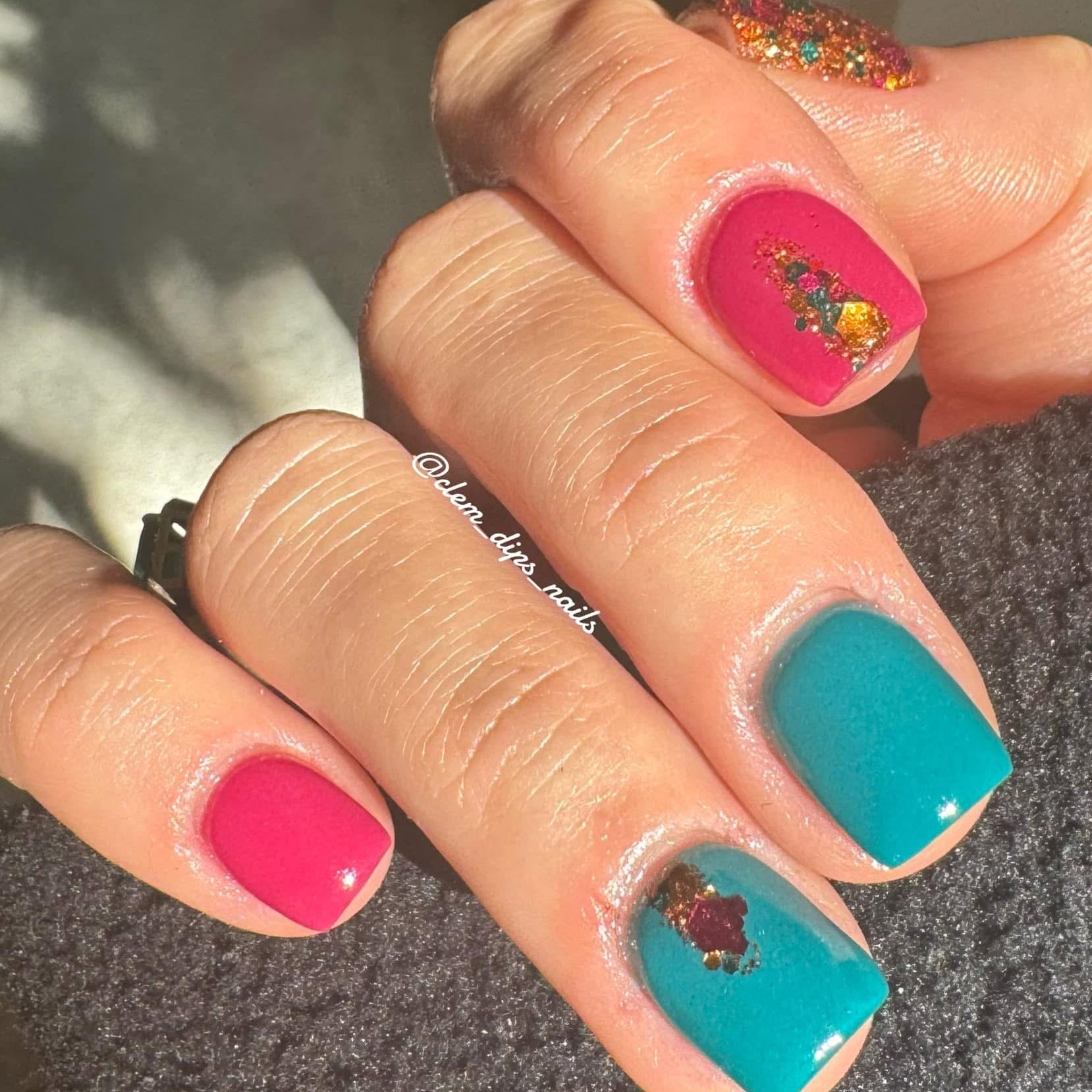 Bright hot pink and teal nails with glitter and floral nail art accents on short square tips.