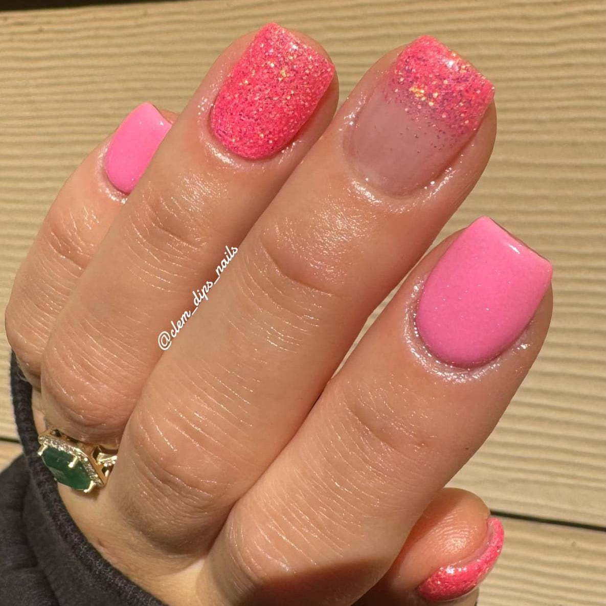 Pink nails with glossy neon shimmer and fine iridescent glitter accents on two fingers.