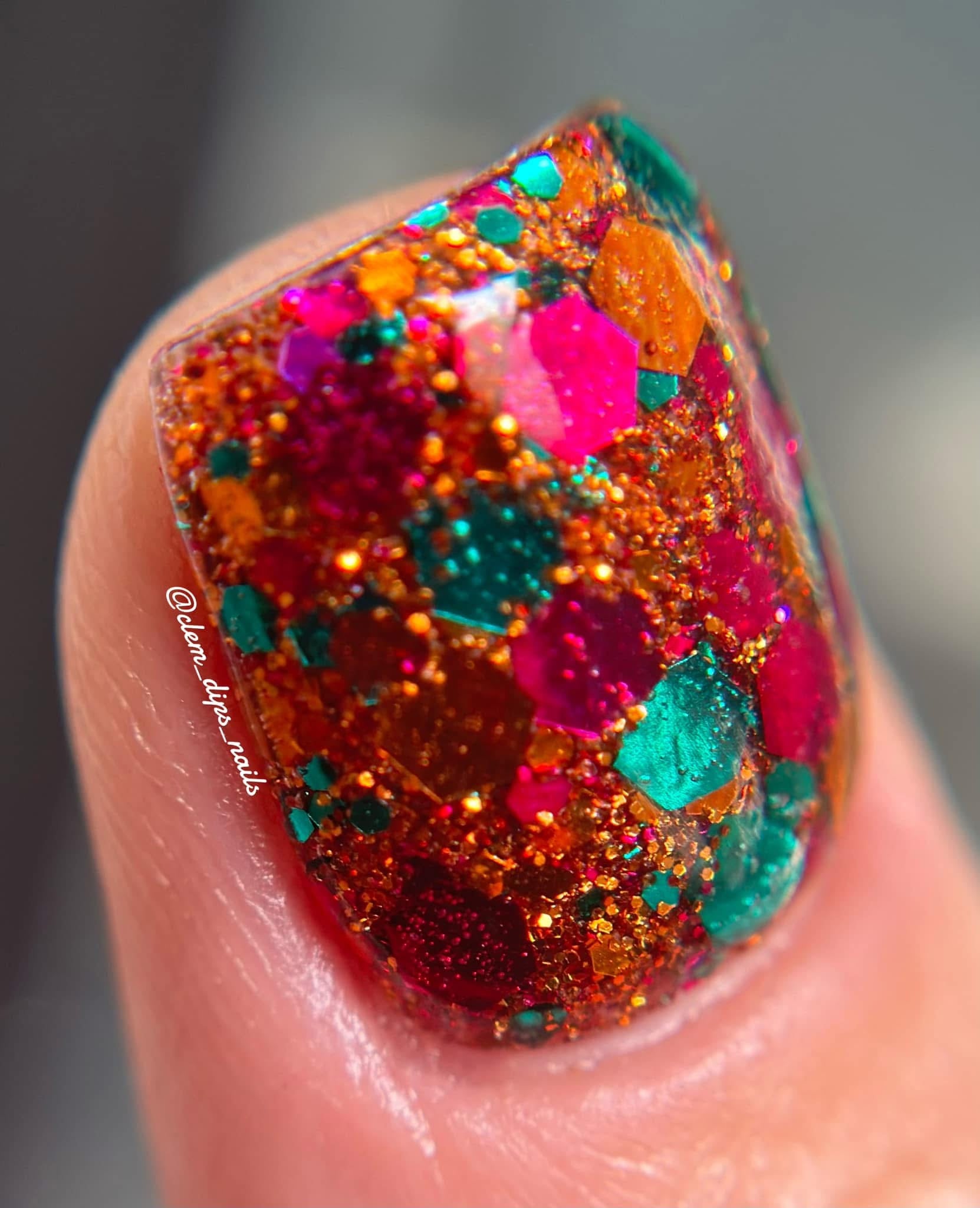 Nail tip with chunky glitter dip powder in vibrant orange, pink, and teal colors.