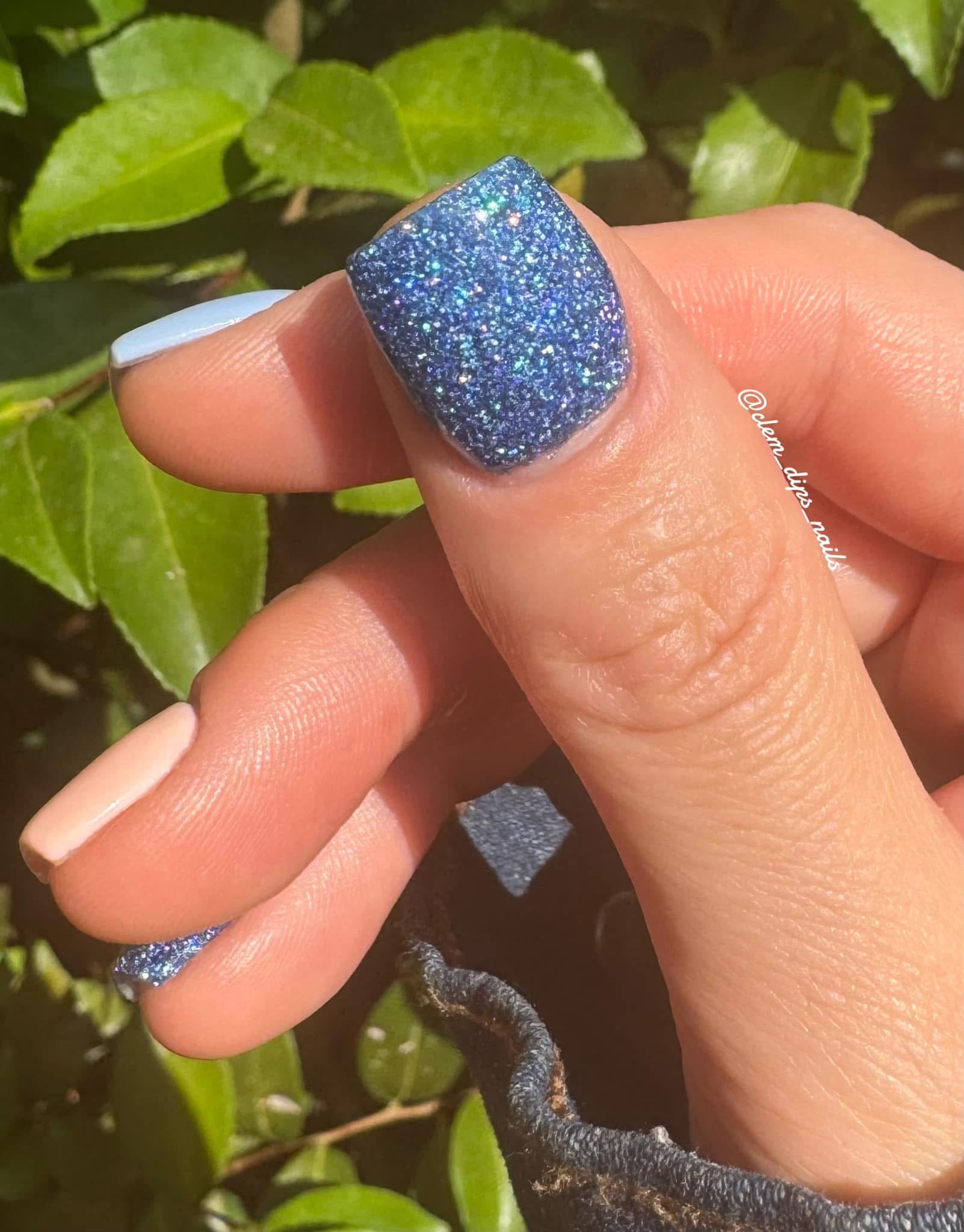 Holographic blue glitter dip powder on nails with fine sparkling shimmer.
