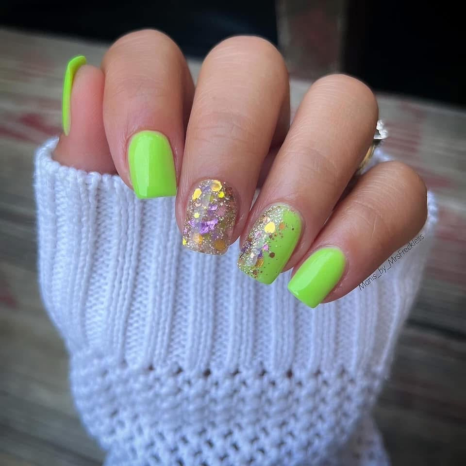 Neon green solid dip powder nails with glitter accent nails on short almond shape.
