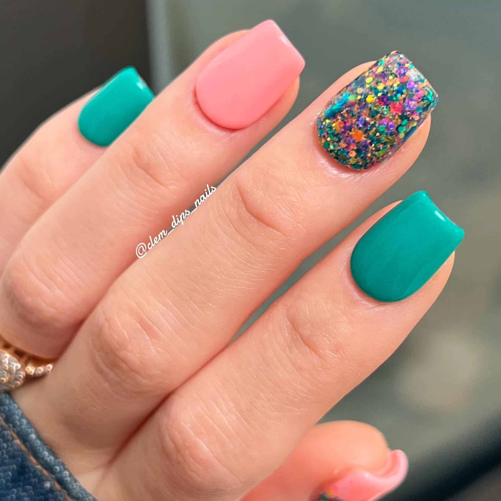Square nails painted teal green, soft pink, and multicolor glitter on ring finger.