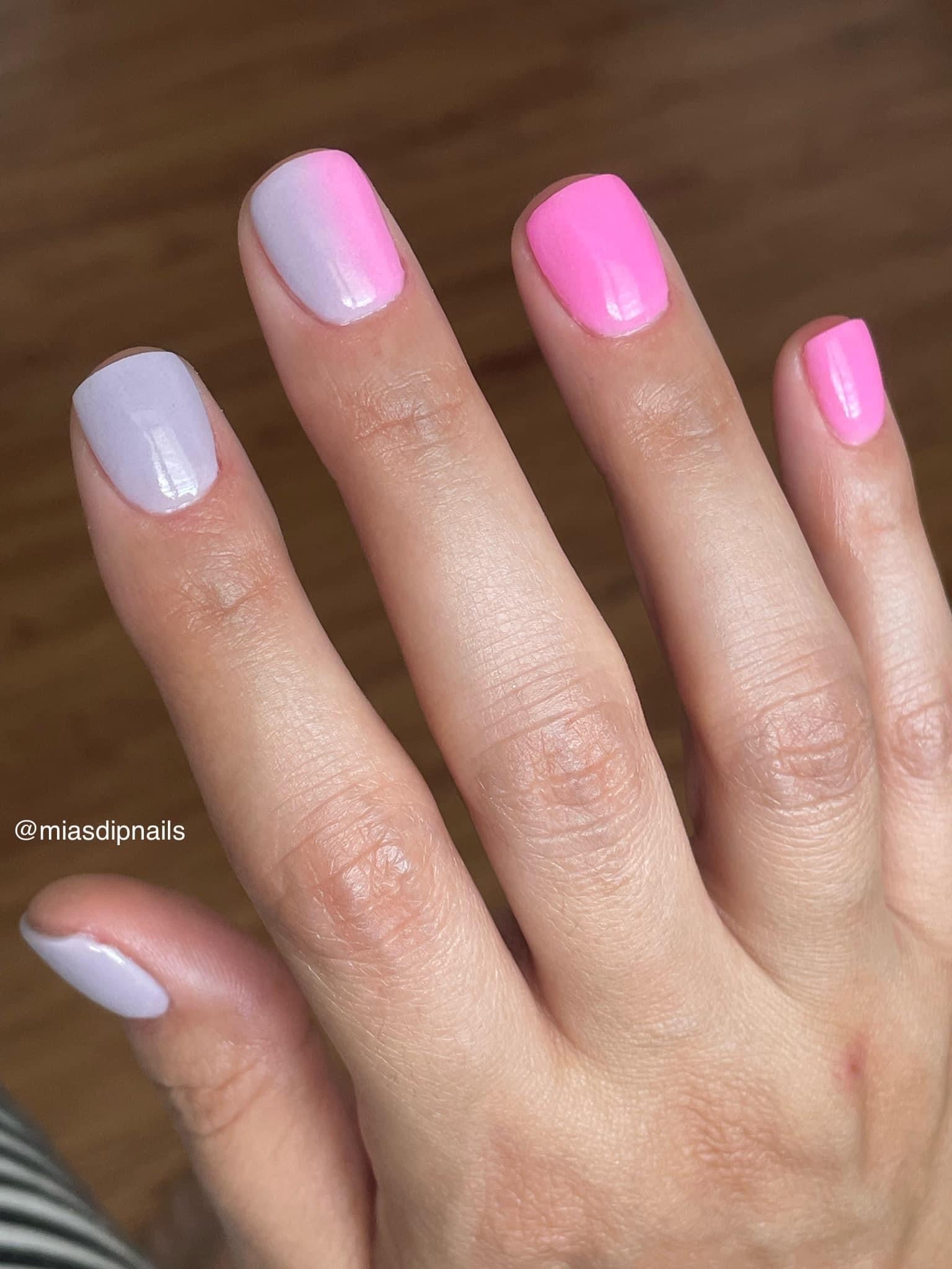 Hand with nails painted in gradient shades of lilac and pink dip powder polish.