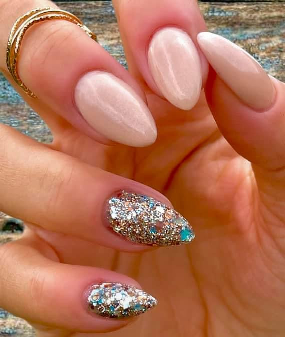 Long almond-shaped nails with soft pink polish and accent nails featuring chunky silver and copper glitter with a touch of.