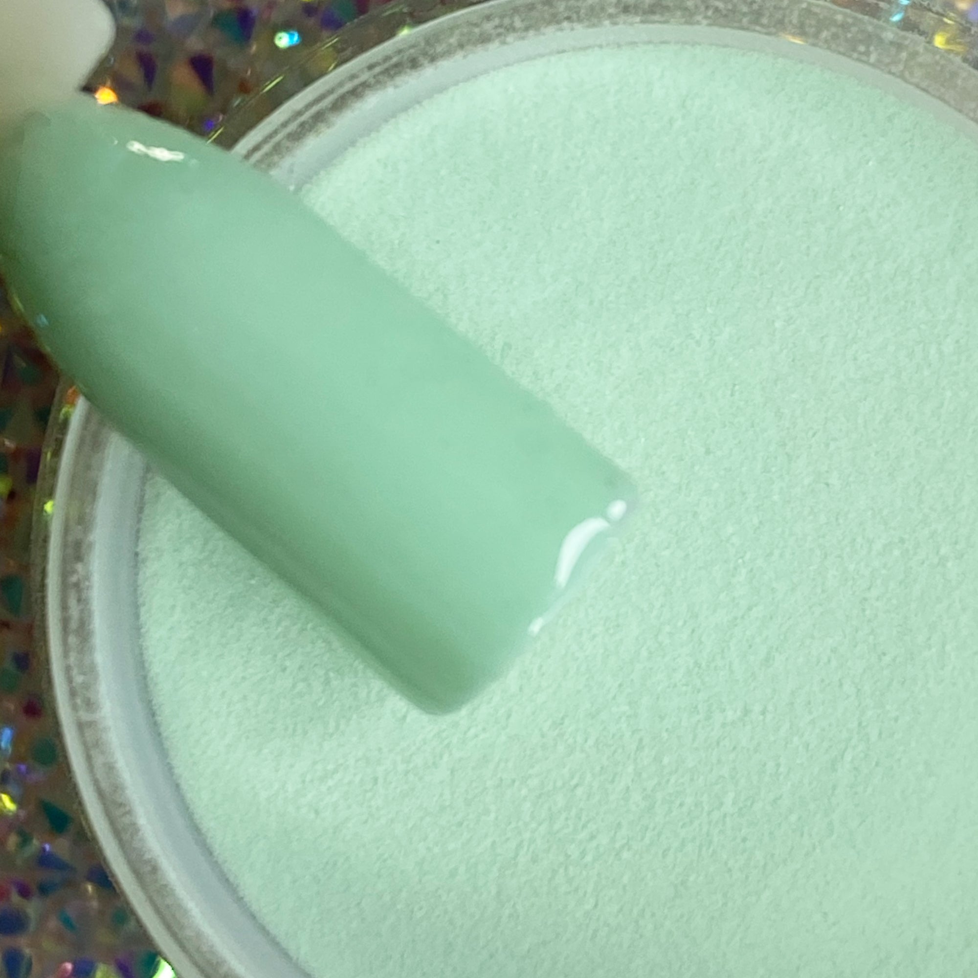 Light blue solid dip powder labeled DP02 Atlantis in a clear container with a nail swatch dipped in the powder.