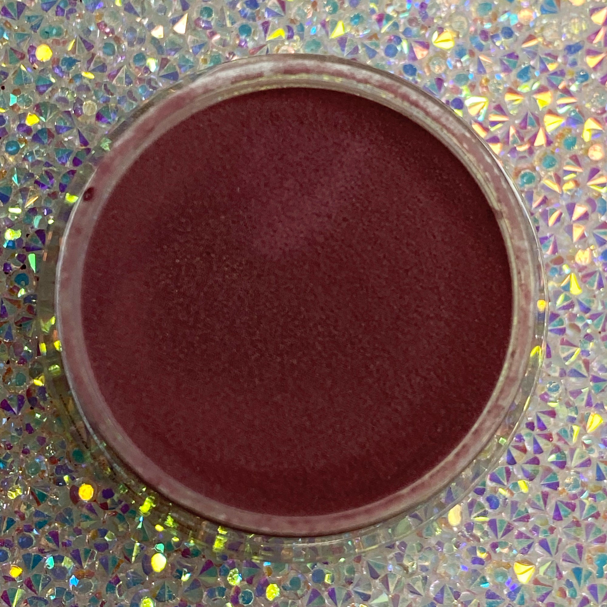 Deep wine purple dip powder in a round clear container on a holographic background.