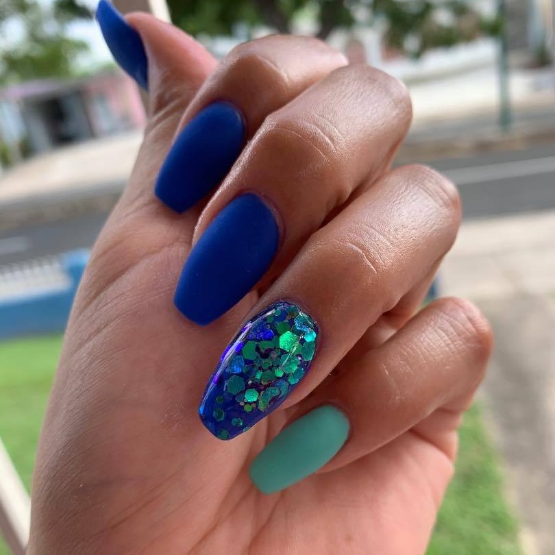 Matte teal and solid blue dip powder nails with a blue glitter accent nail in round shapes.