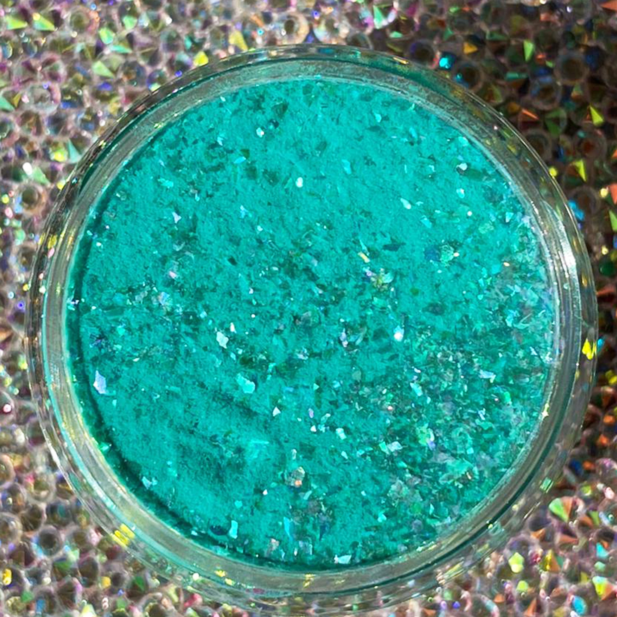 Teal dip powder with green and blue iridescent chameleon flakes in a clear round container.
