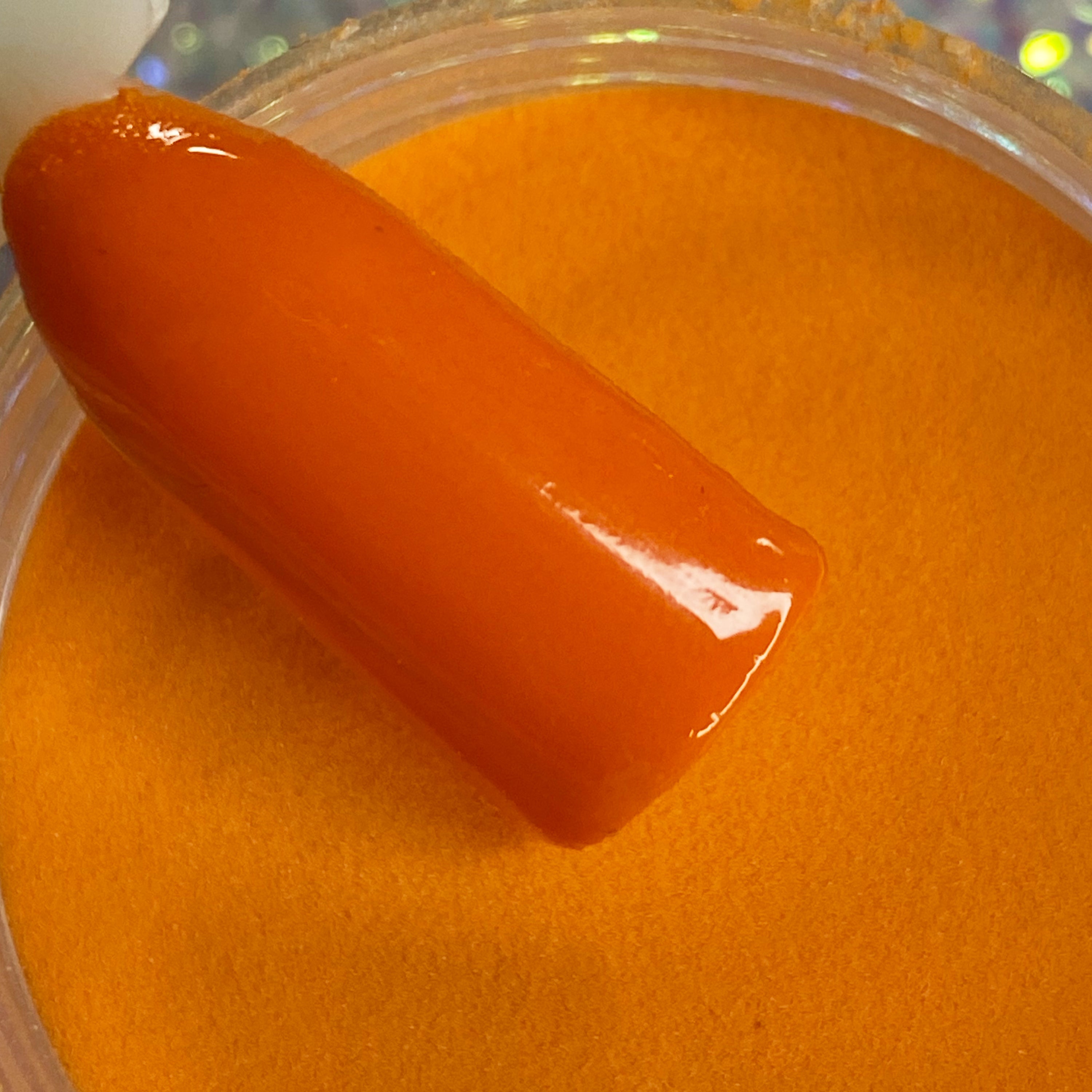 Vibrant glossy orange dip powder nail polish with smooth, solid color finish.