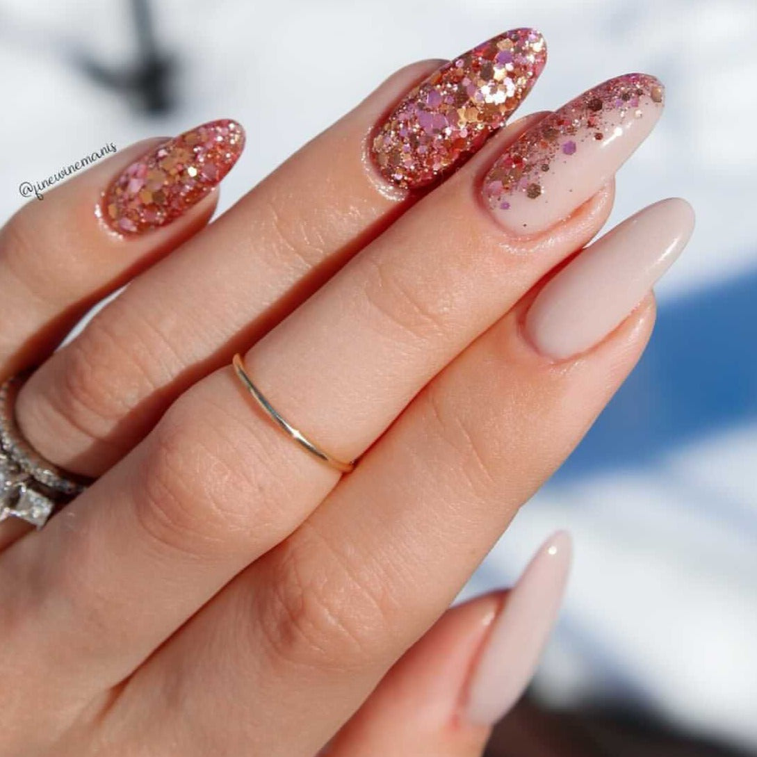 Almond-shaped nails with beige and nude dip powder, two nails feature rose gold glitter accents.