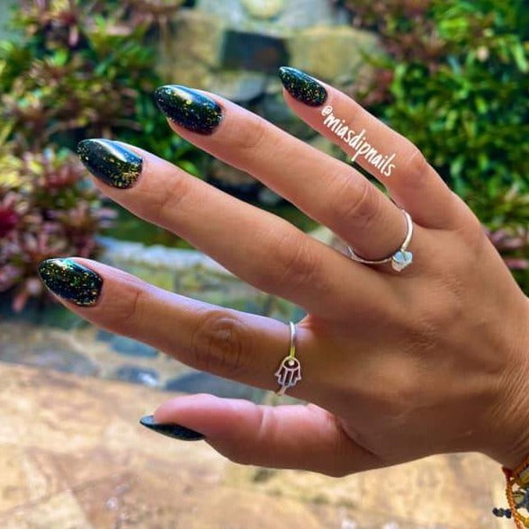 Black stiletto nails with multicolor chameleon flakes creating a shimmering effect.