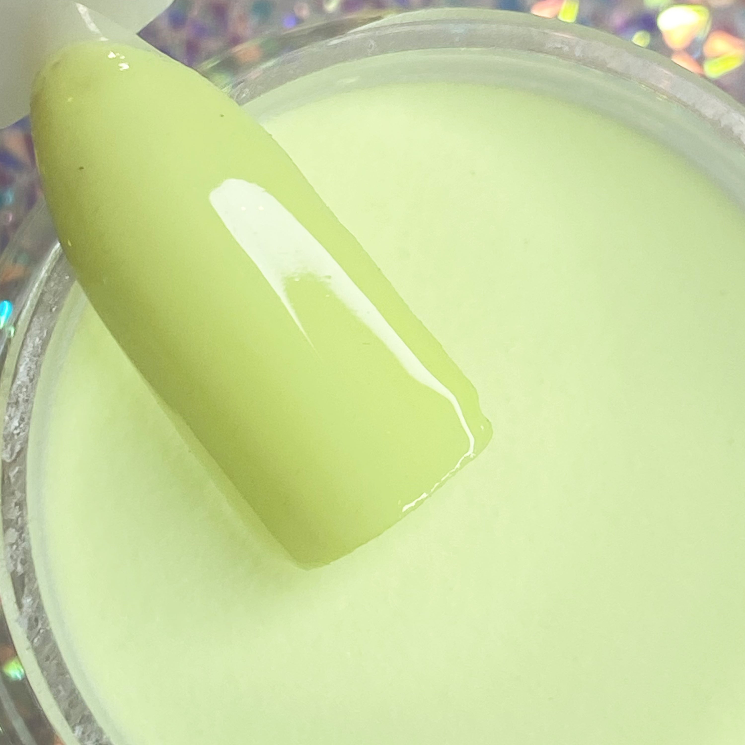 Pale pistachio green dip powder with smooth, creamy finish on nail swatch stick.