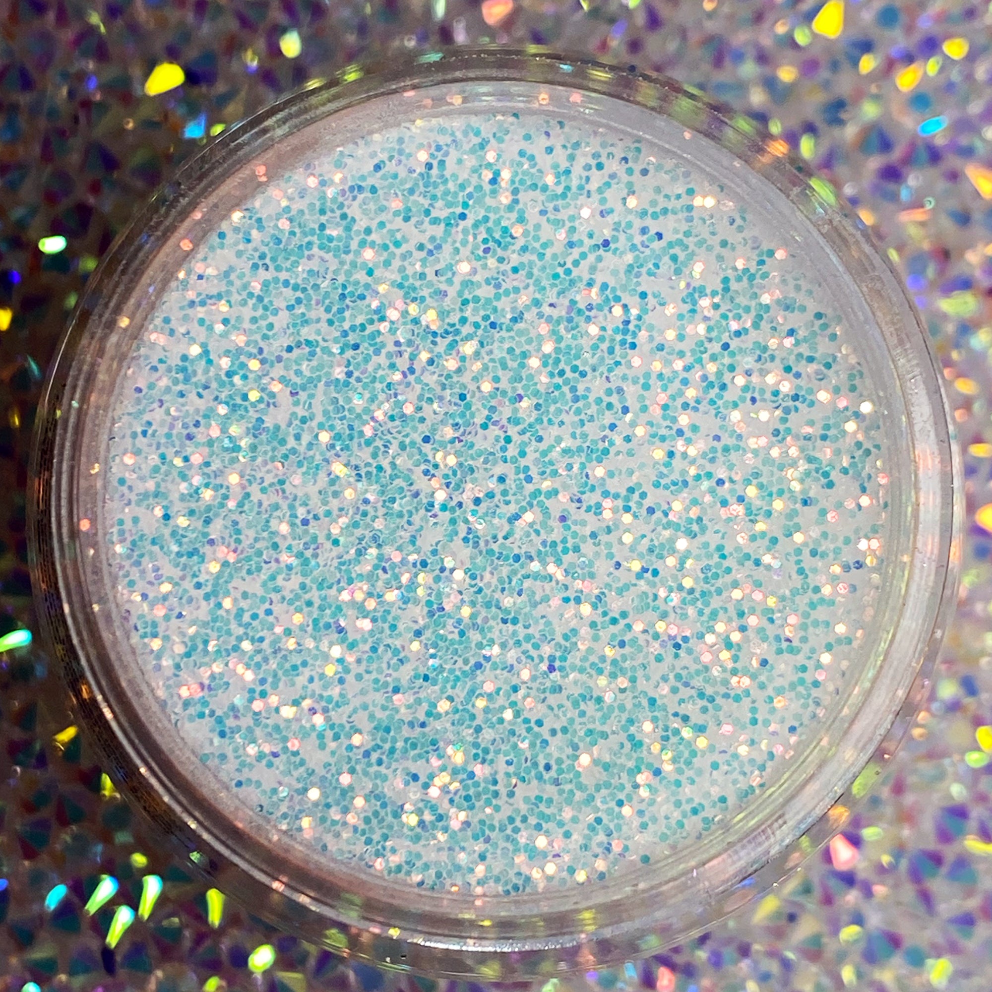 Clear jar filled with fine iridescent white glitter powder with blue and silver sparkles.