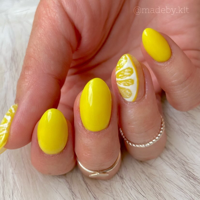 Bright neon yellow almond-shaped nails with white accent nails featuring delicate yellow petal designs.