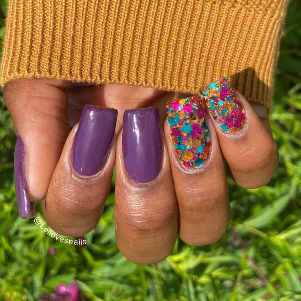 Glossy plum purple nails with a multicolor chunky glitter accent nail on ring finger.