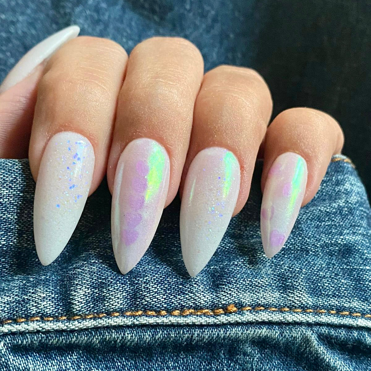 Long almond-shaped nails with white iridescent glow-in-the-dark powder over a solid base.
