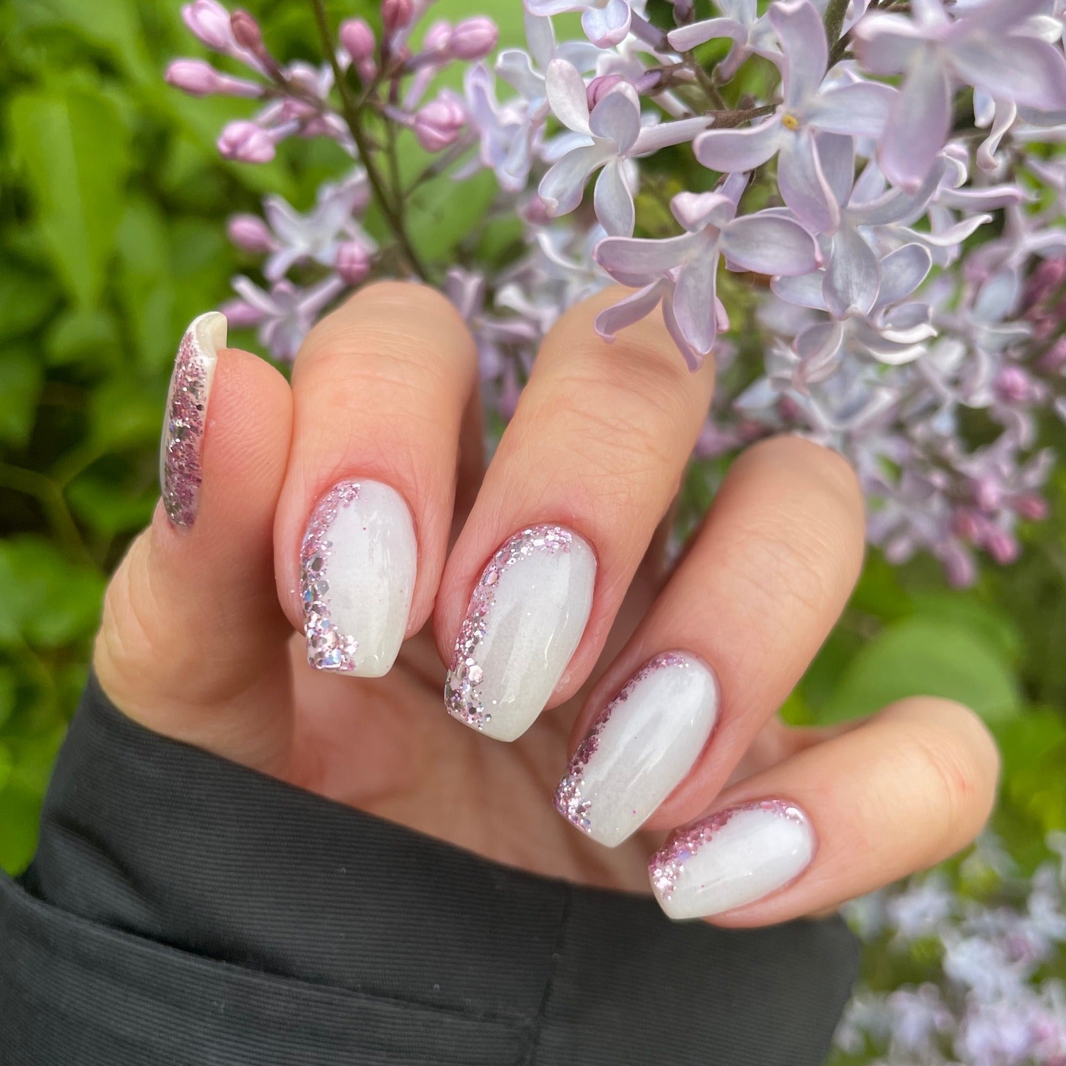 Long coffin nails with white glow-in-the-dark polish and silver glitter accents on pinky and ring fingers.