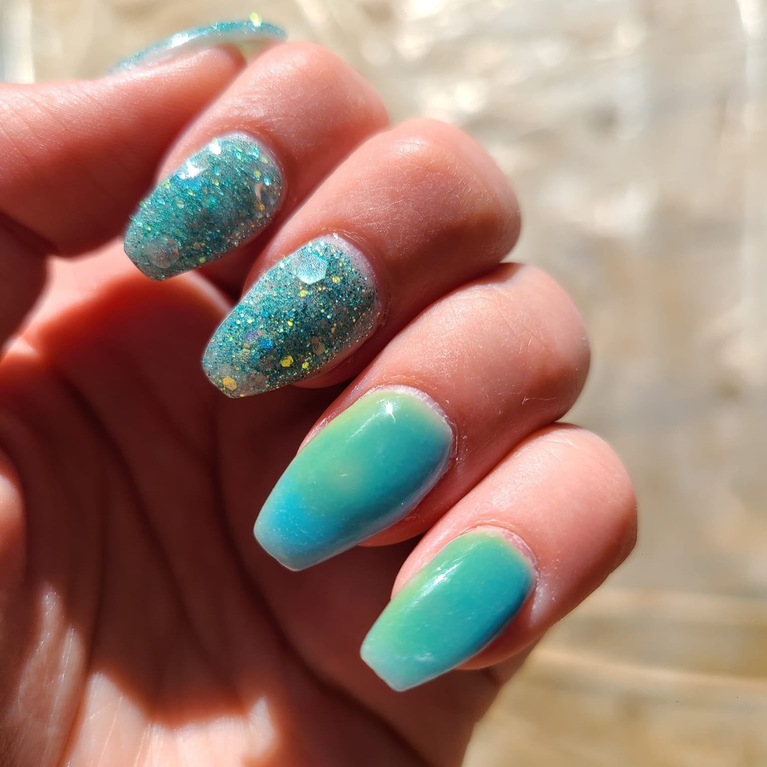 Bright blue and green ombre nails with sparkle and a smooth glossy finish.