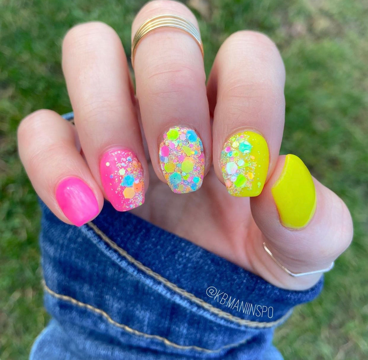 Multicolor chunky glitter nail polish on medium-length nails with pink and yellow bases, spring design.
