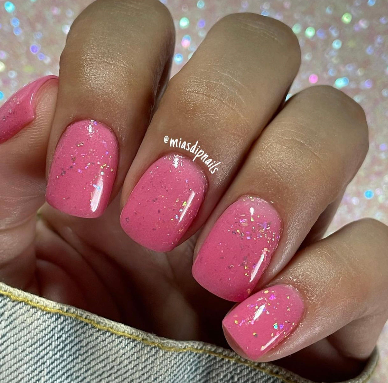 Bright pink solid nail polish with subtle glitter on short square nails.