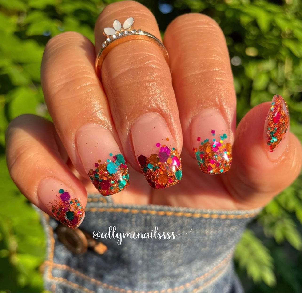 Nails with chunky multicolor glitter in orange, pink, teal, and berry tones over natural base.