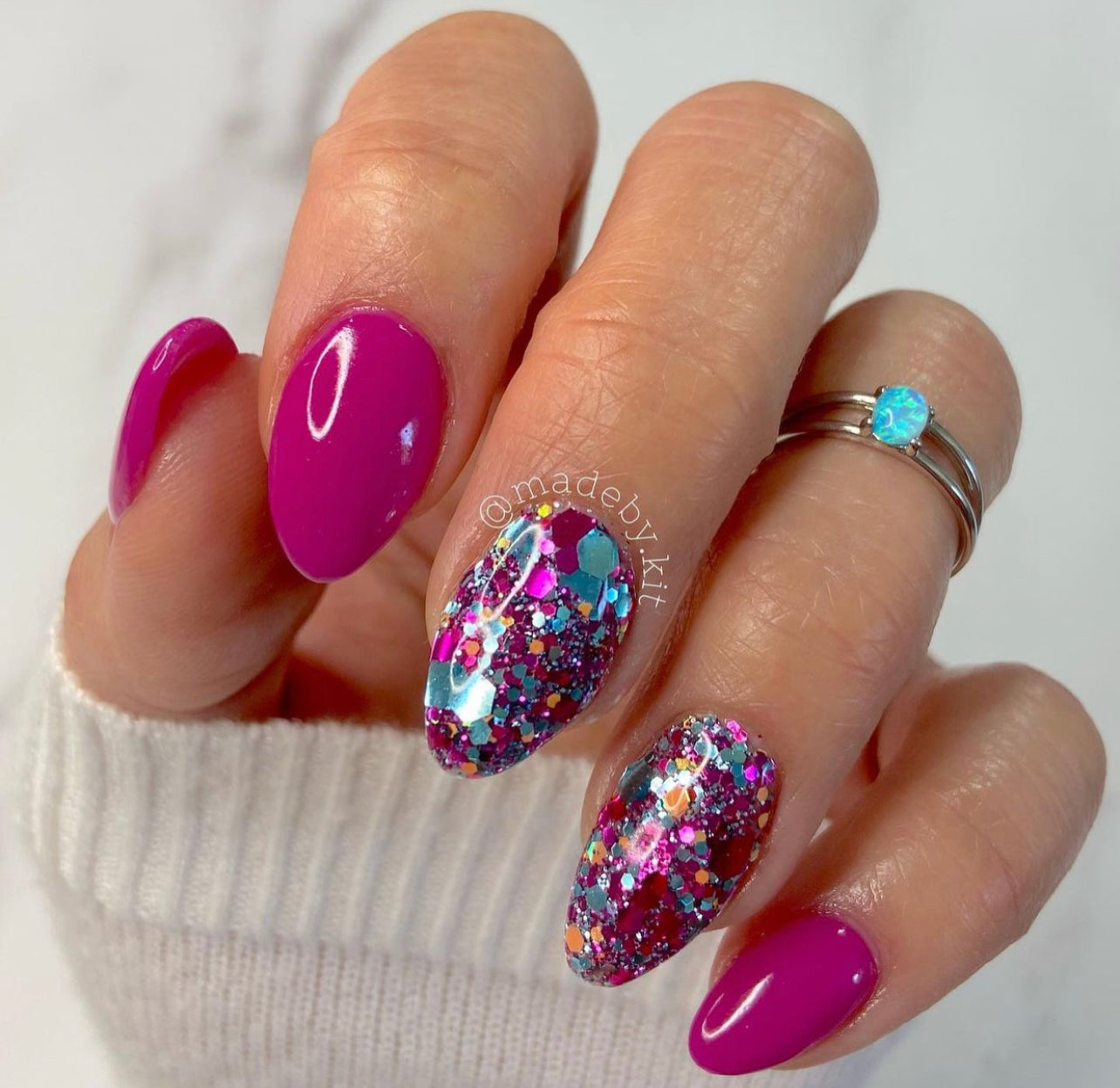 Bright pink nails with two accent nails featuring chunky multicolor glitter over a clear base.