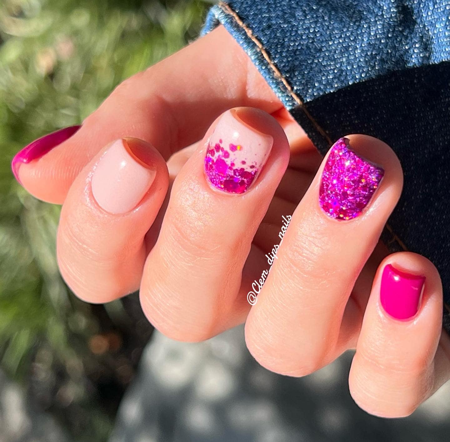 Manicured hand with pink and nude nails, featuring solid pink, glitter gradient, and full glitter designs.