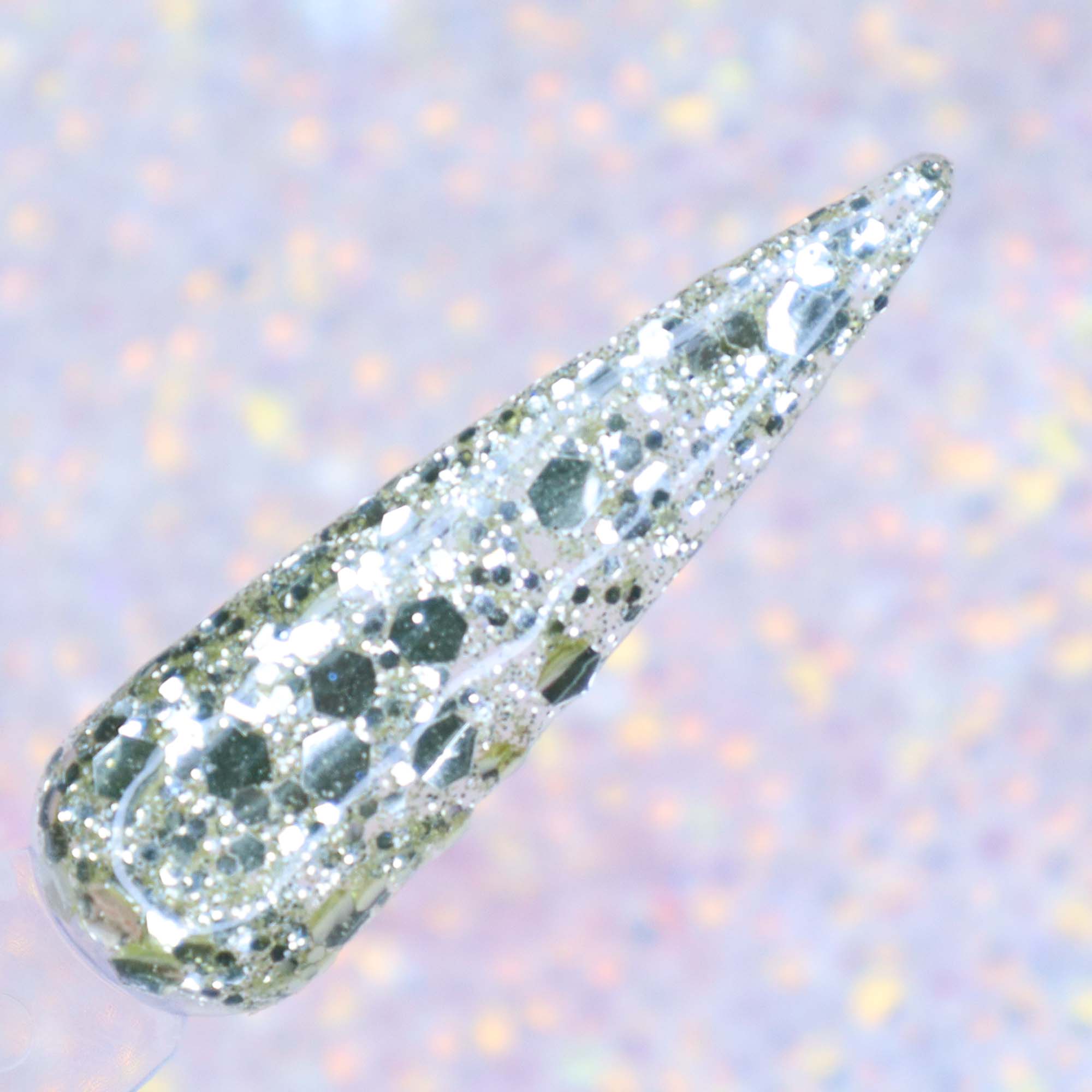 Clear nail tip coated with chunky silver glitter in various sizes against a soft iridescent background.