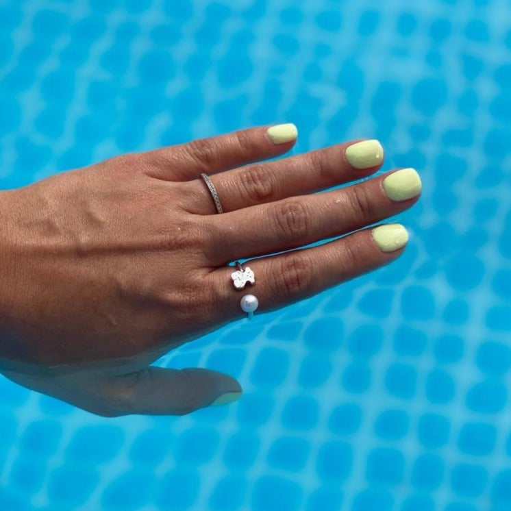 Hand with pistachio green dip powder nails against a blue tiled pool background.