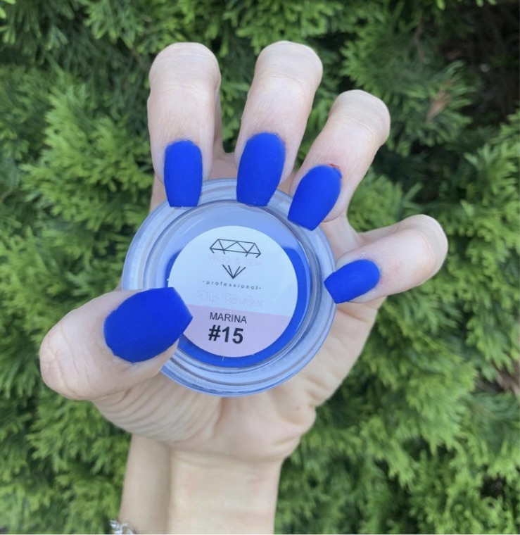 Hand with bright matte royal blue nails holding a round container labeled Marina #15 dip powder.