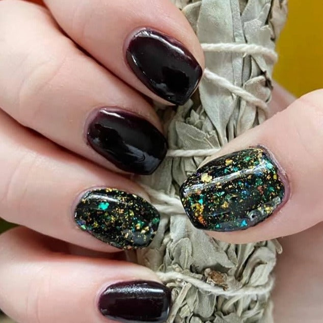 Glossy black nails with multicolor chameleon flakes on accent nails.