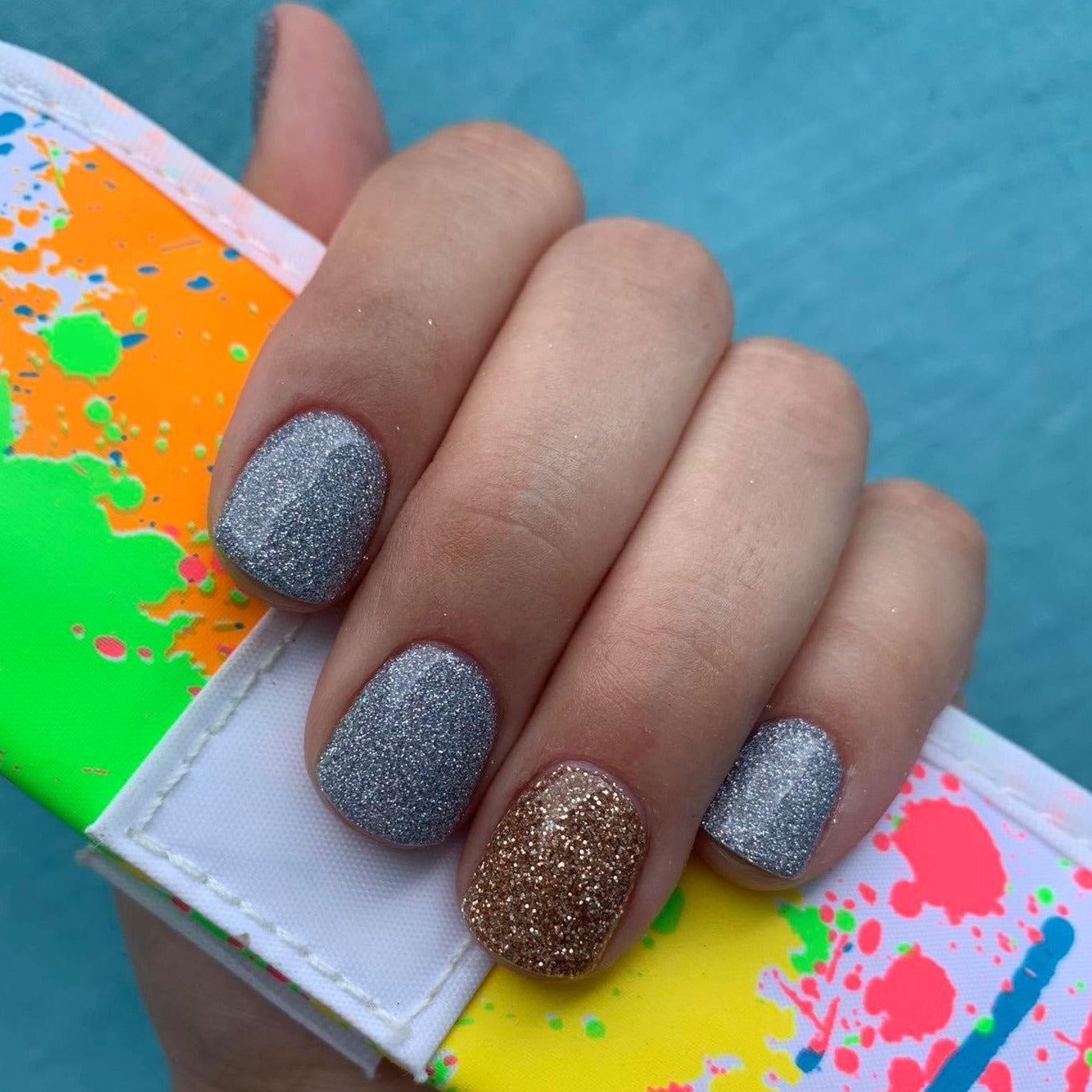 Matte gray nails with fine holographic glitter and one accent nail in metallic bronze glitter polish.