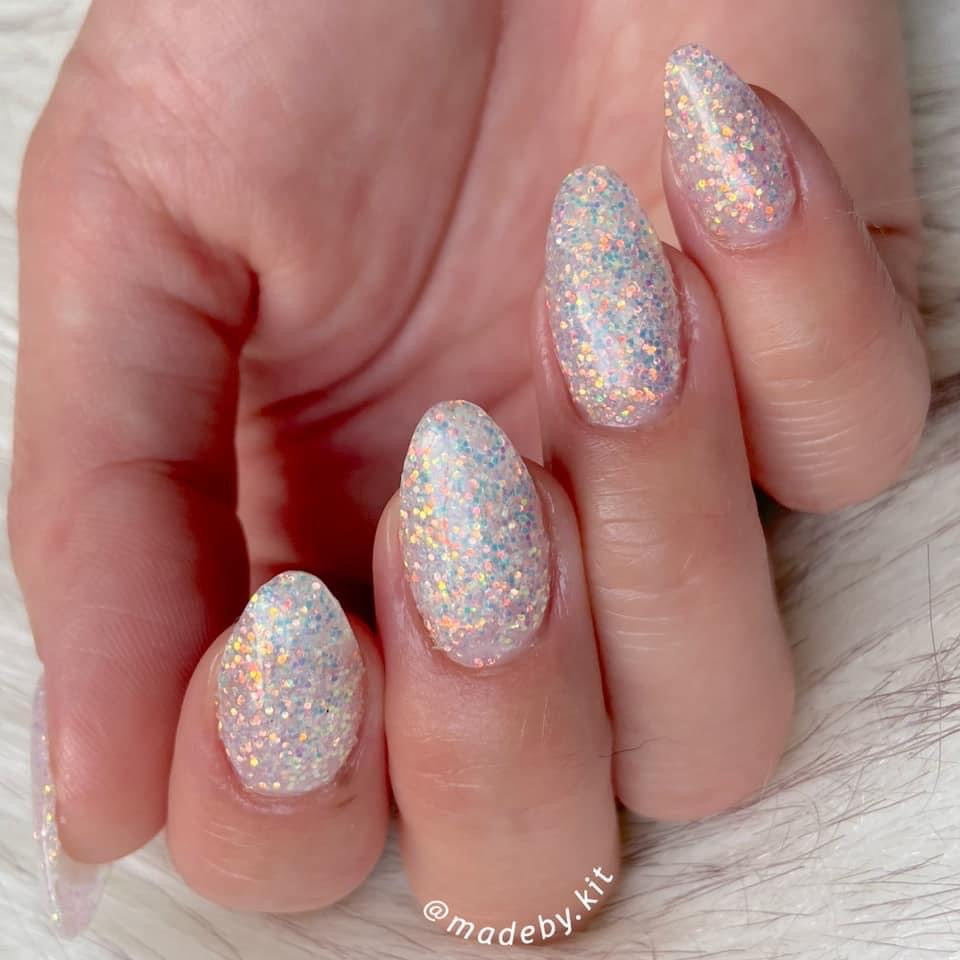Almond-shaped nails with fine iridescent white glitter dip powder creating a sparkling glazed effect.