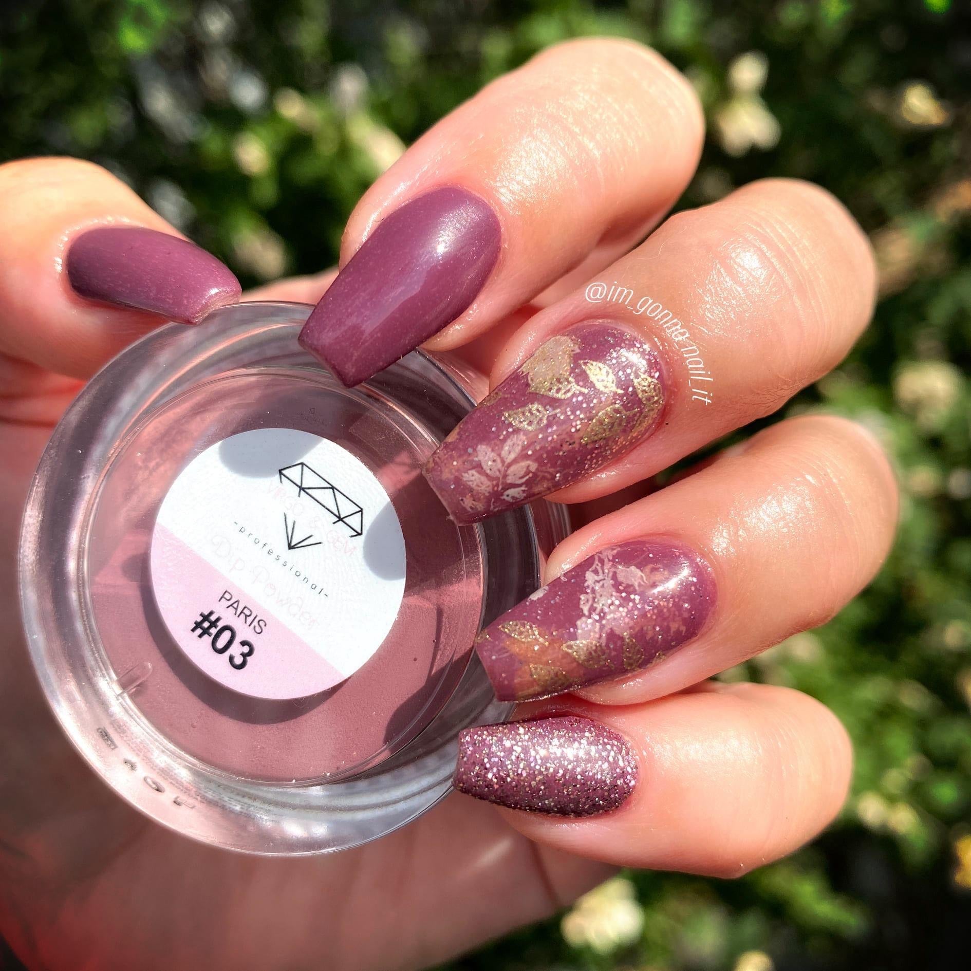 Hand holding jar of deep wine purple dip powder with long nails featuring solid, glitter, and floral accent designs.