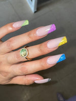 Nude acrylic nails with vibrant fine glitter tips in green, purple, yellow, blue, and silver.