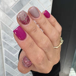 Hand with pink and glittery nails dip powder against a tiled wall background