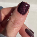 Burgundy glittery nail polish with fine shimmer on short square nails.