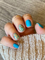 Bright blue nails with chunky multicolor glitter accent nails featuring gold and teal flakes.