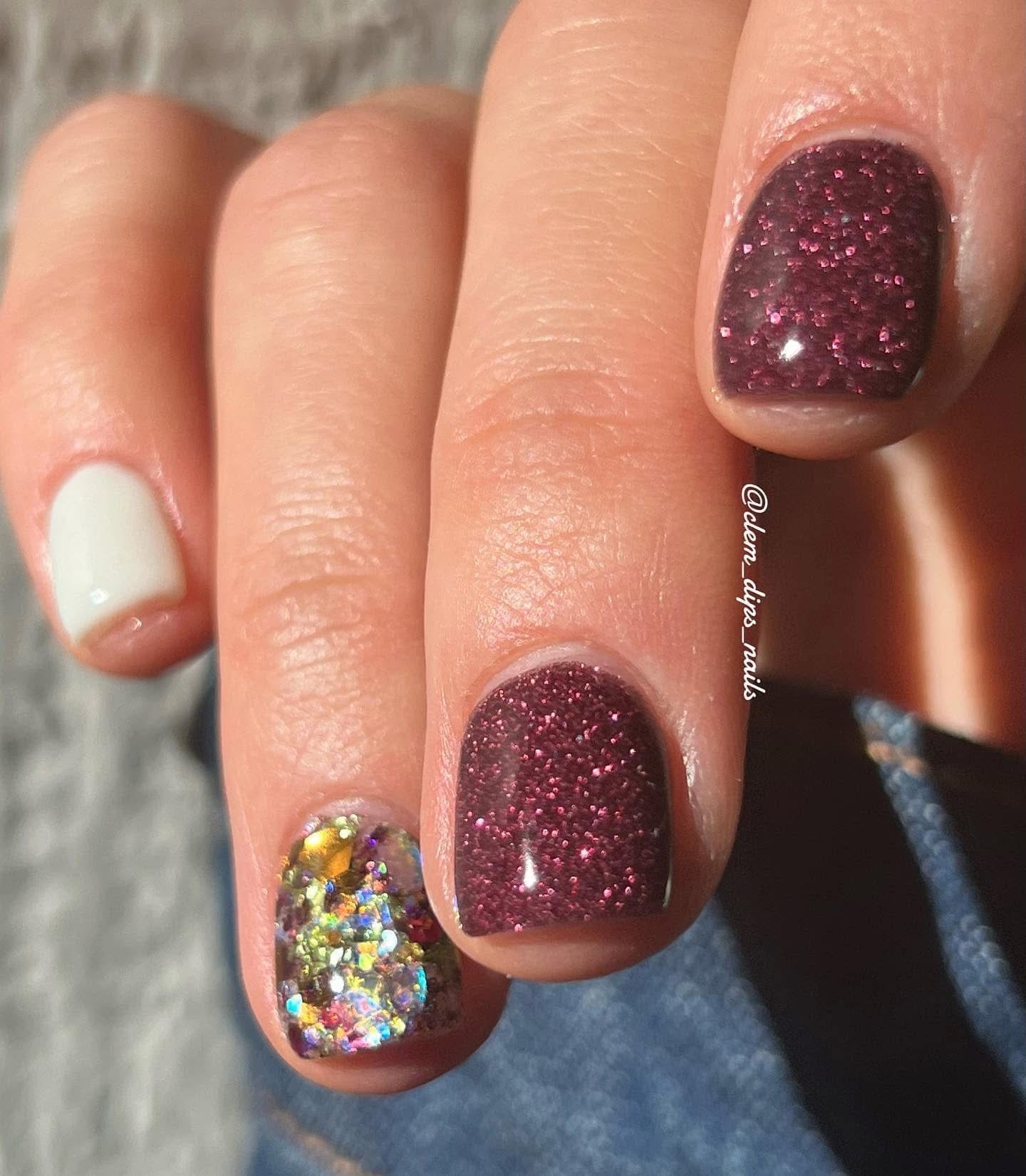 Burgundy glitter dip powder on nails with one accent nail featuring multicolored holographic glitter.
