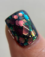 Glossy black nail polish with chunky multicolor glitter in pink, green, blue, and gold tones.