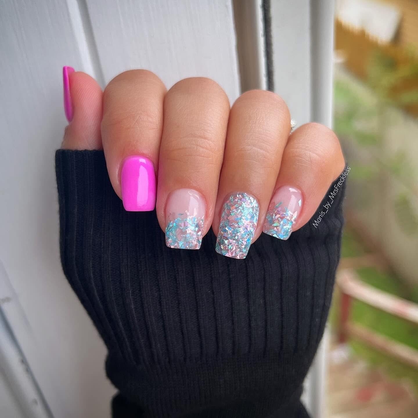 Hand with nails showing hot pink solid color on thumb and pastel blue glitter dip powder on other nails.