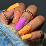 Hand with vibrant nails featuring DP341 Lilac Haze glitter dip powder, orange, and pink shades, showcasing a creative nail design.