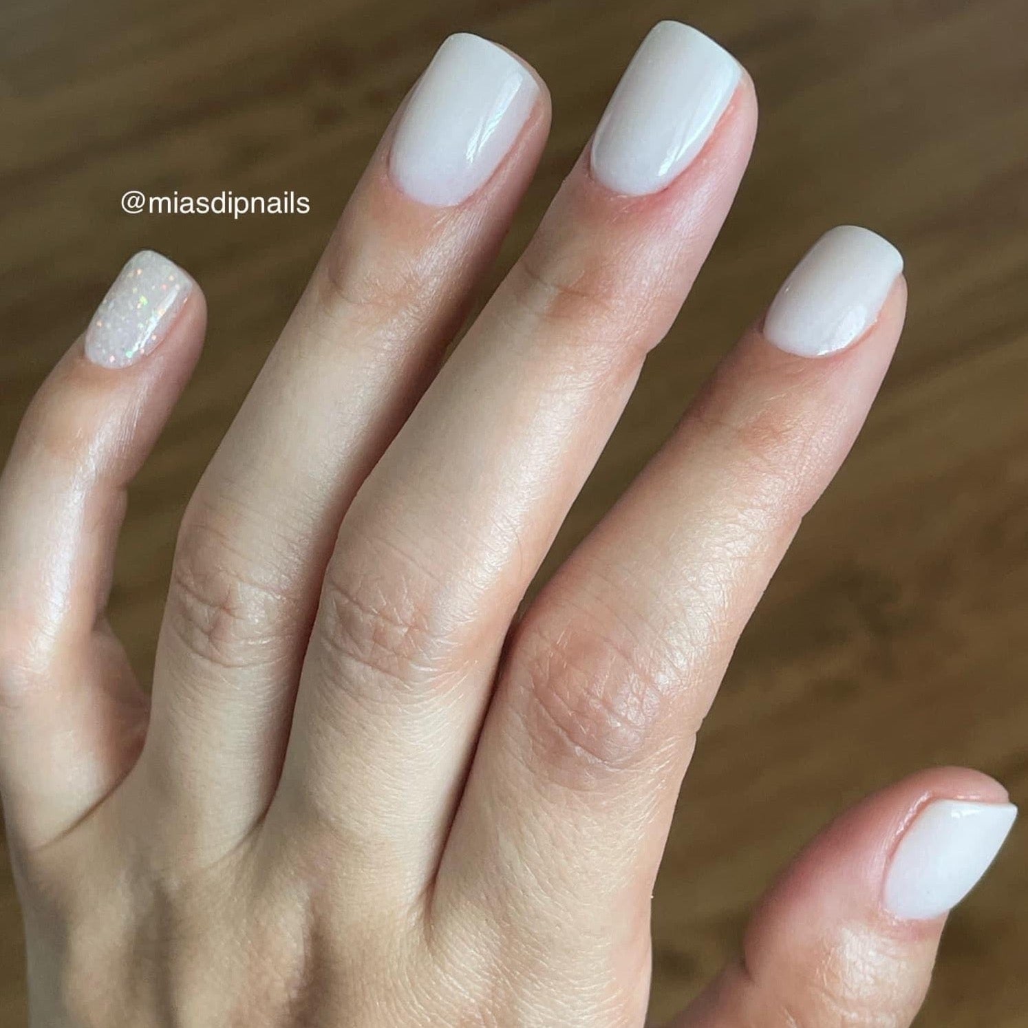 Glossy pale nude dip powder manicure on short square nails with subtle shimmer on ring finger.