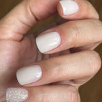 Short natural white gel nails with one accent nail featuring fine iridescent glitter polish.