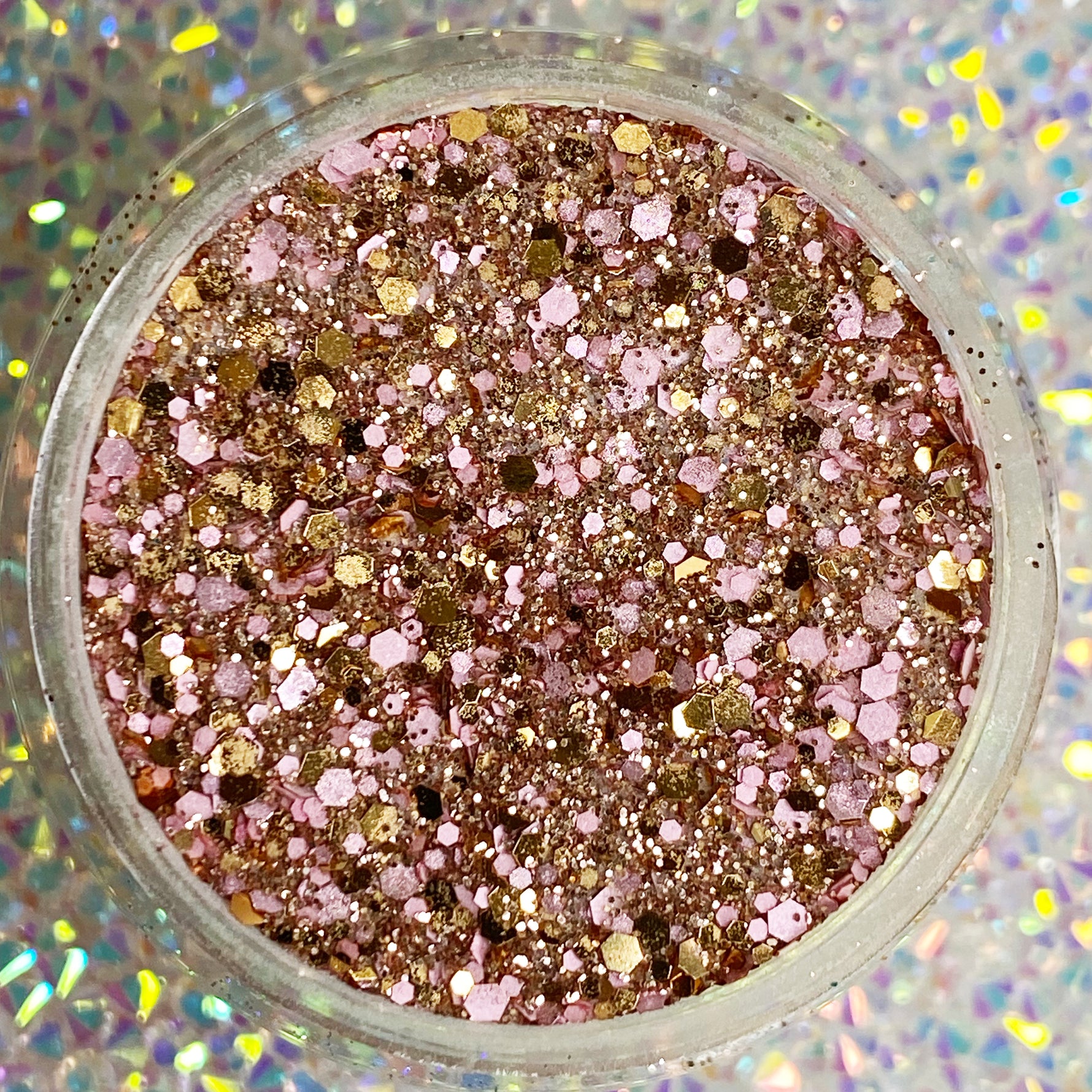 Chunky pink, gold, and rose gold glitter dip powder with mixed-size sparkles in clear round container.