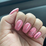 Glossy rose pink dip powder nails with thin black vertical line accents on short, rounded nails.