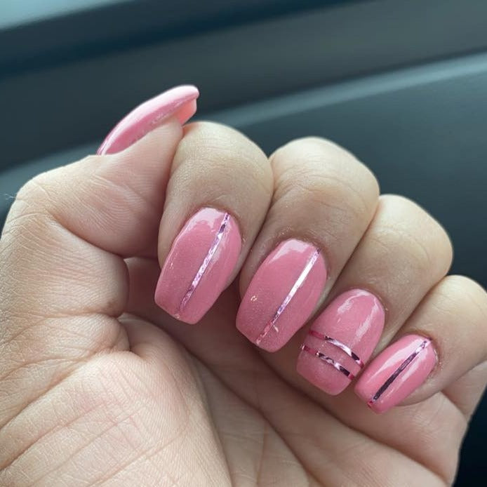 Glossy rose pink dip powder nails with thin black vertical line accents on short, rounded nails.
