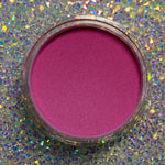 Open jar of vibrant hot pink dip powder on iridescent glitter background.